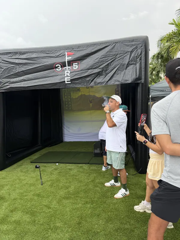 Guests gathered under the canopy beside the simulator at an outdoor event